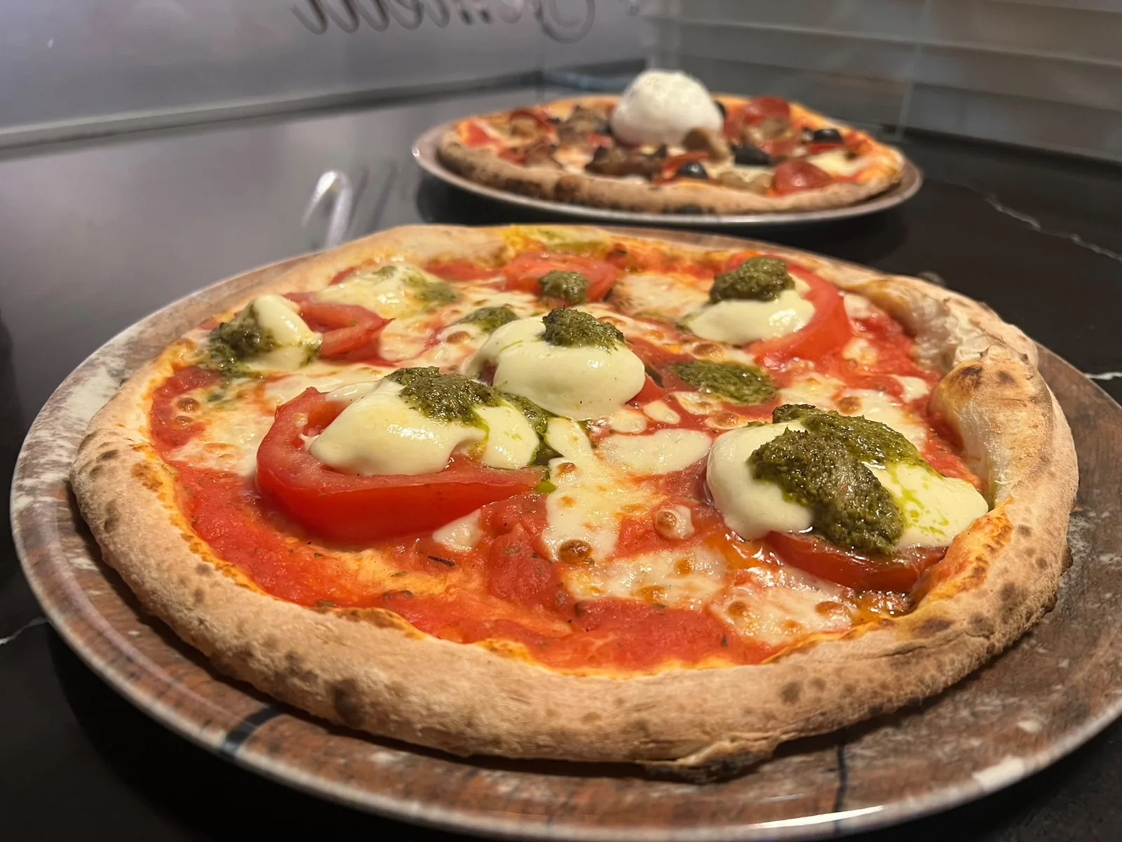 Pizza Caprese mit Mozzarella, Tomaten und grünem Pesto