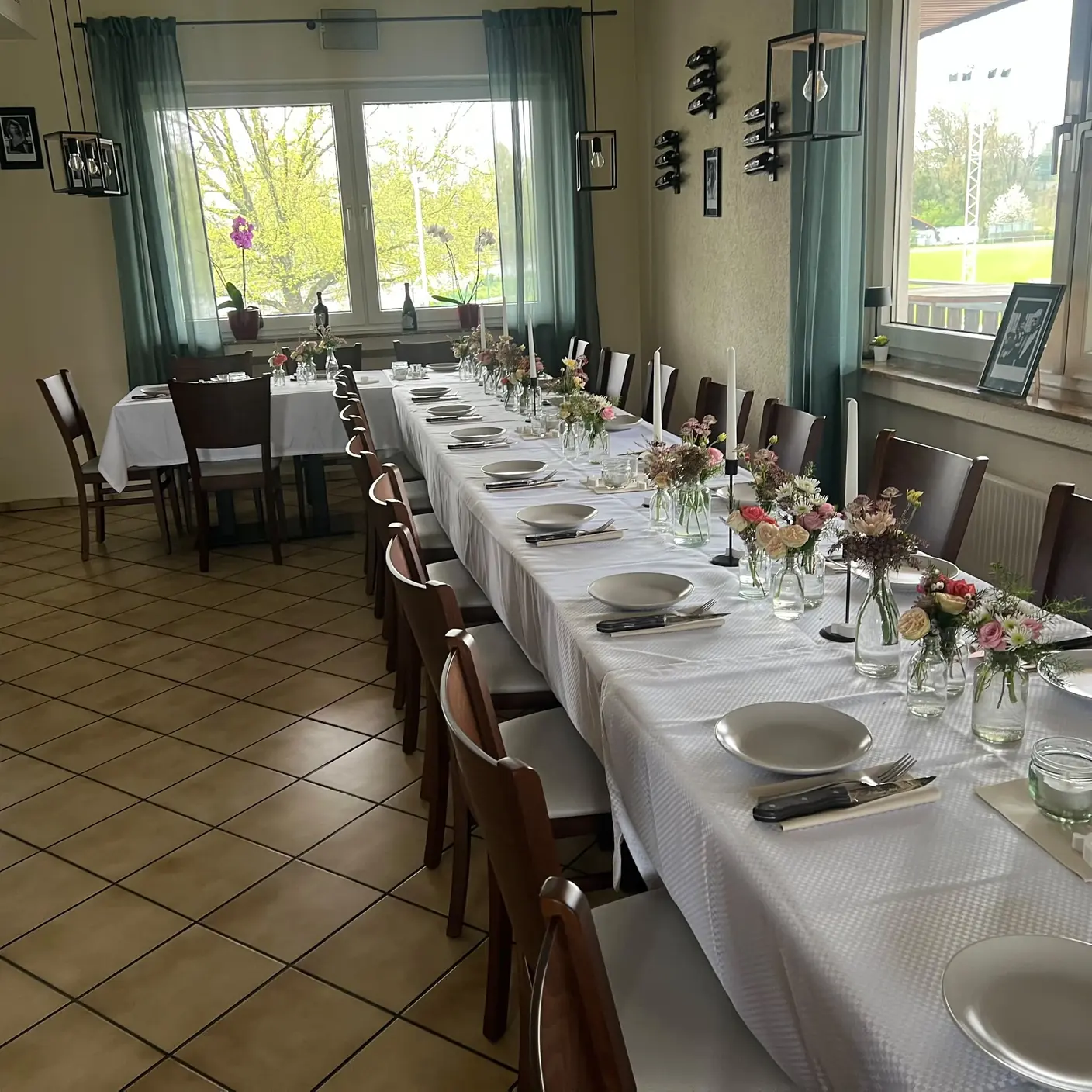 Festlich eingedeckte Tafel mit Blumen, Kerzen und Blick auf den Sportplatz