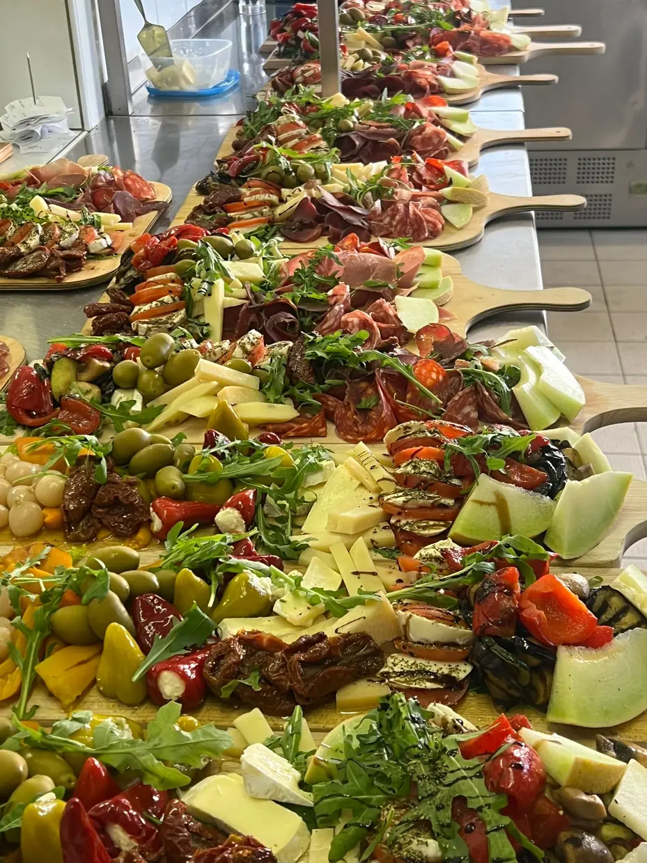 Reichhaltiges Antipasti-Buffet auf langen Holzbrettern mit Käse, Wurst, Oliven und Gemüse